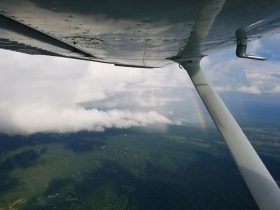 a view from a plane window looking down on cloud covered green hills.